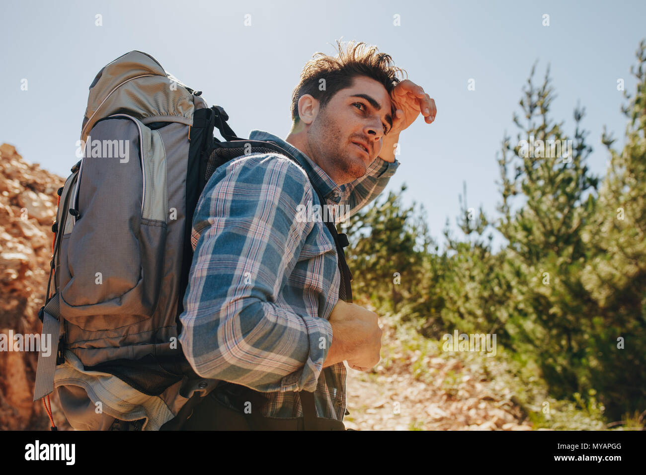 Male hiker trekking on mountains. Young man exploring nature walking through mountain trails. Stock Photo
