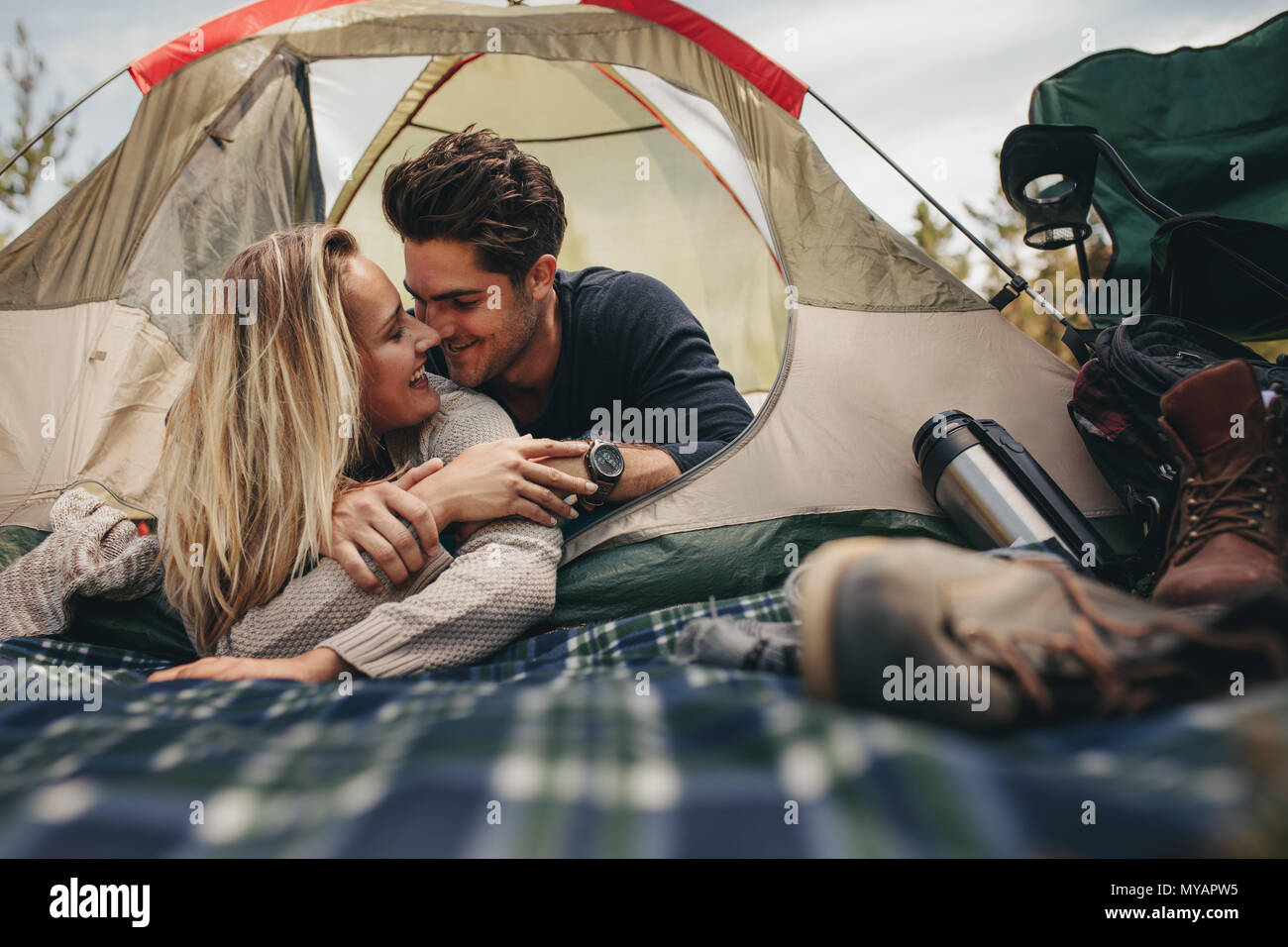 Happy man and woman having a romantic moment in a tent. Couple camping in  nature Stock Photo - Alamy