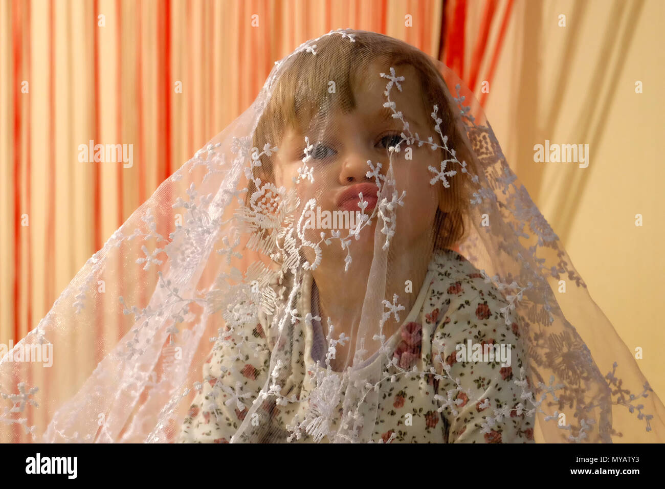 Little girl put out her lips for a kiss, covered with a veil Stock Photo