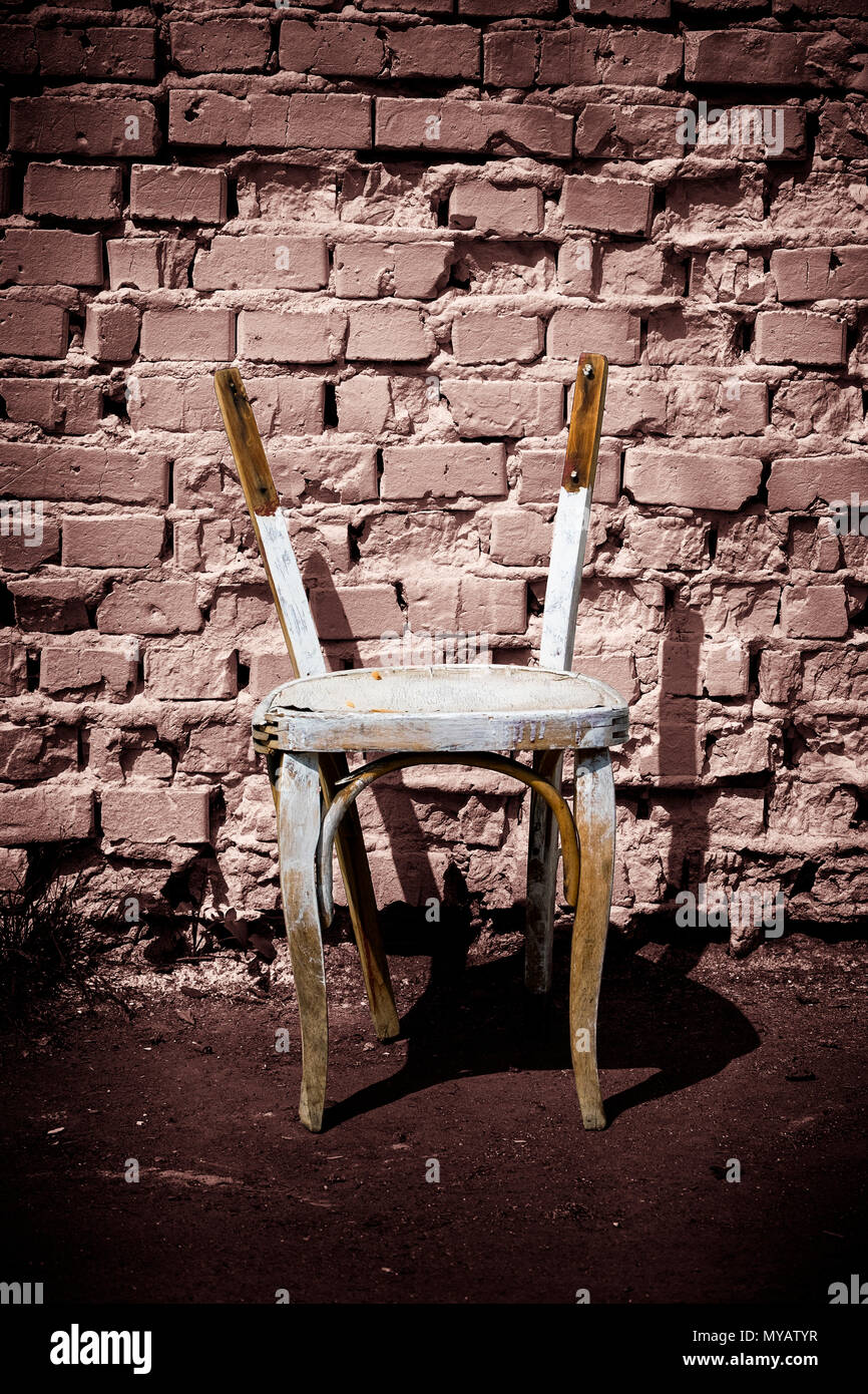 Old wooden chair without backrest against a brick wall background Stock