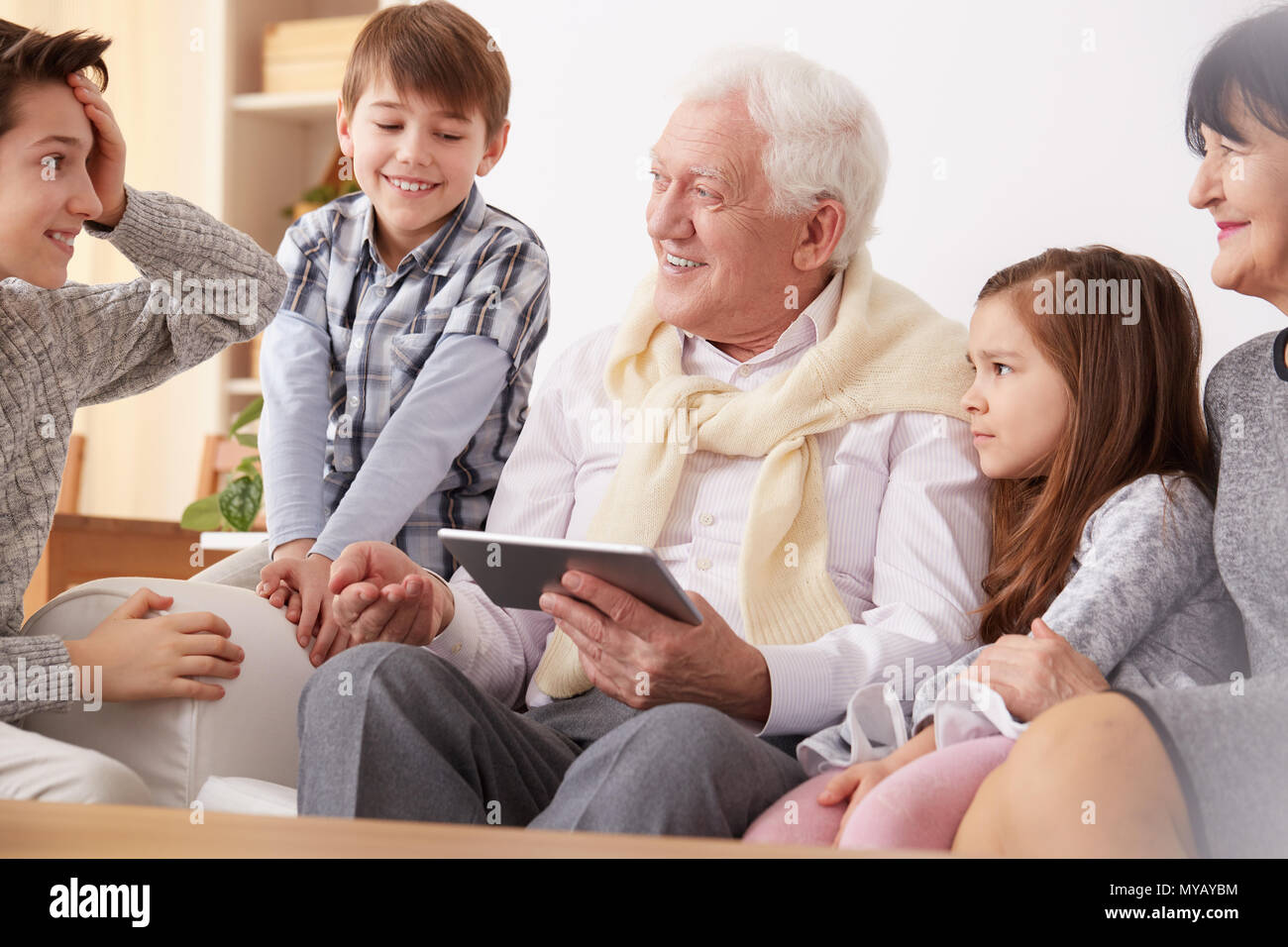 Happy grandchildren teaching grandpa to use a tablet Stock Photo