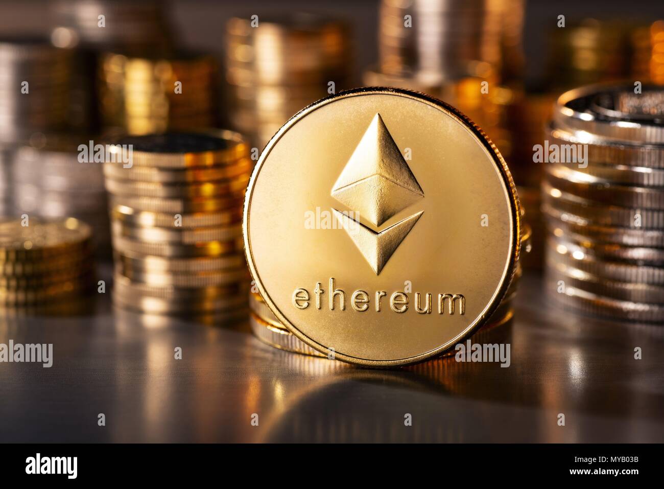 Cryptocurrency coin Ethereum with several stacks of coins in the background | usage worldwide Stock Photo