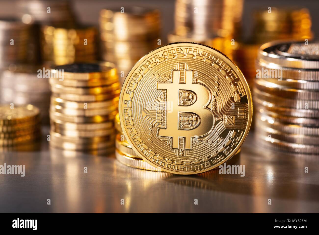 Coin of the crypto-currency Bitcoin with several stacks of coins in the background | usage worldwide Stock Photo