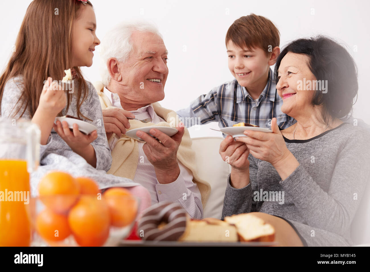 Grandparents and grandchildren smiling and eating a cake Stock Photo