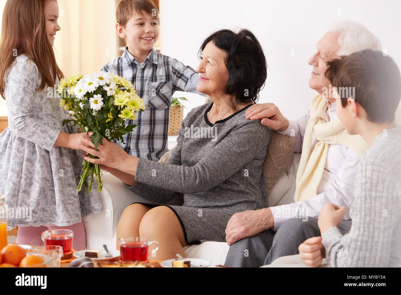 Little girl giving flowers to her happy grandma Stock Photo