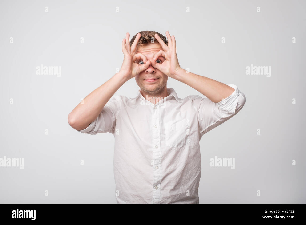 Caucasian man making sign of owl with hands. Stock Photo