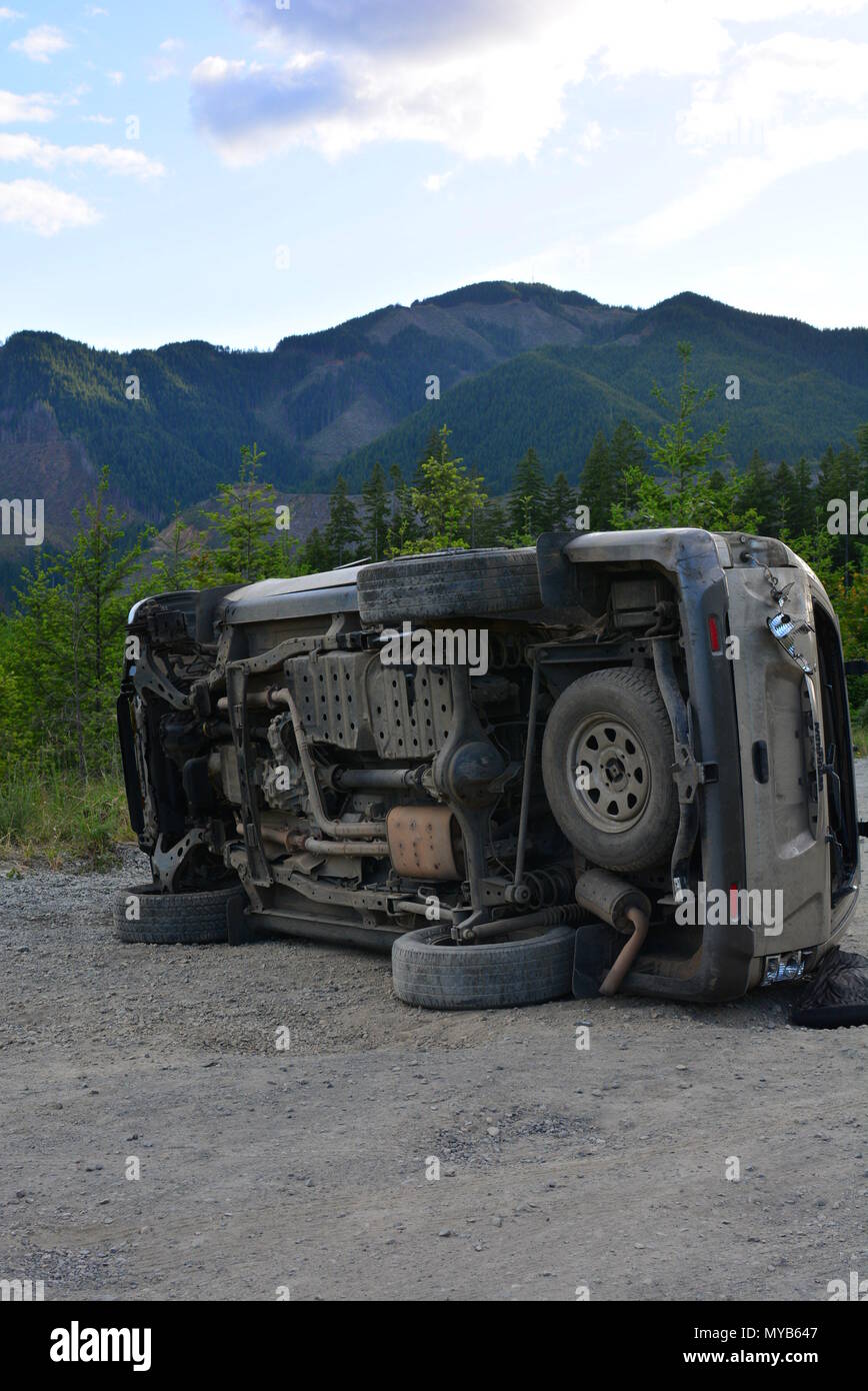 SUV car accident on it's side on a dirt road Stock Photo