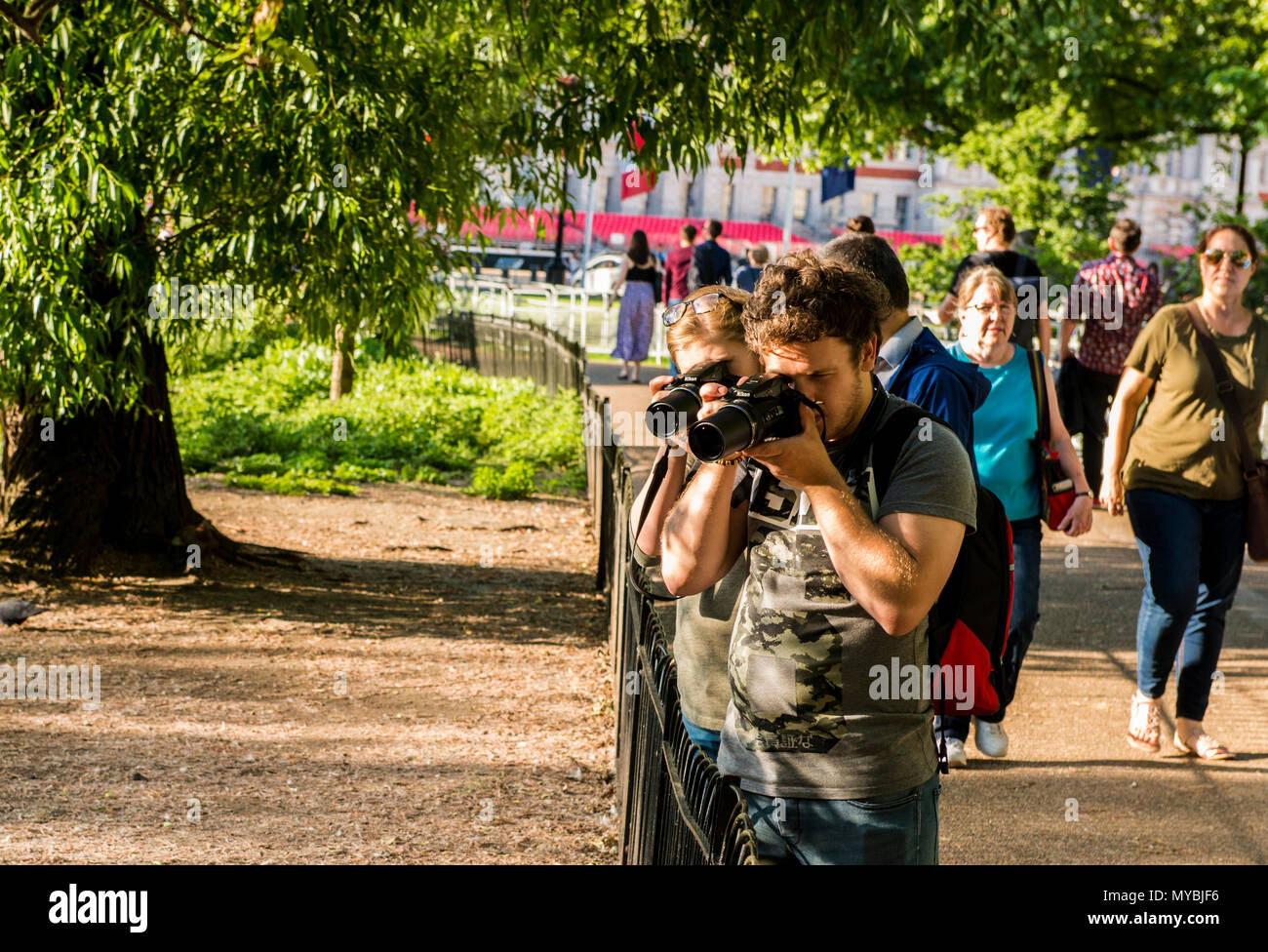 Two people photographing subject out of shot, with long lenses pointed in the same direction, St James's Park, London, England, UK Stock Photo