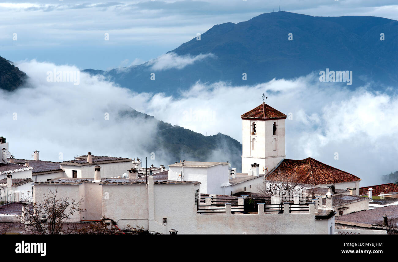 The Alpujarran village of Capileira, with its Catholic church is shrouded in mist, high up in the Sierra Nevada mountains in Spain's Andalucia region. Stock Photo
