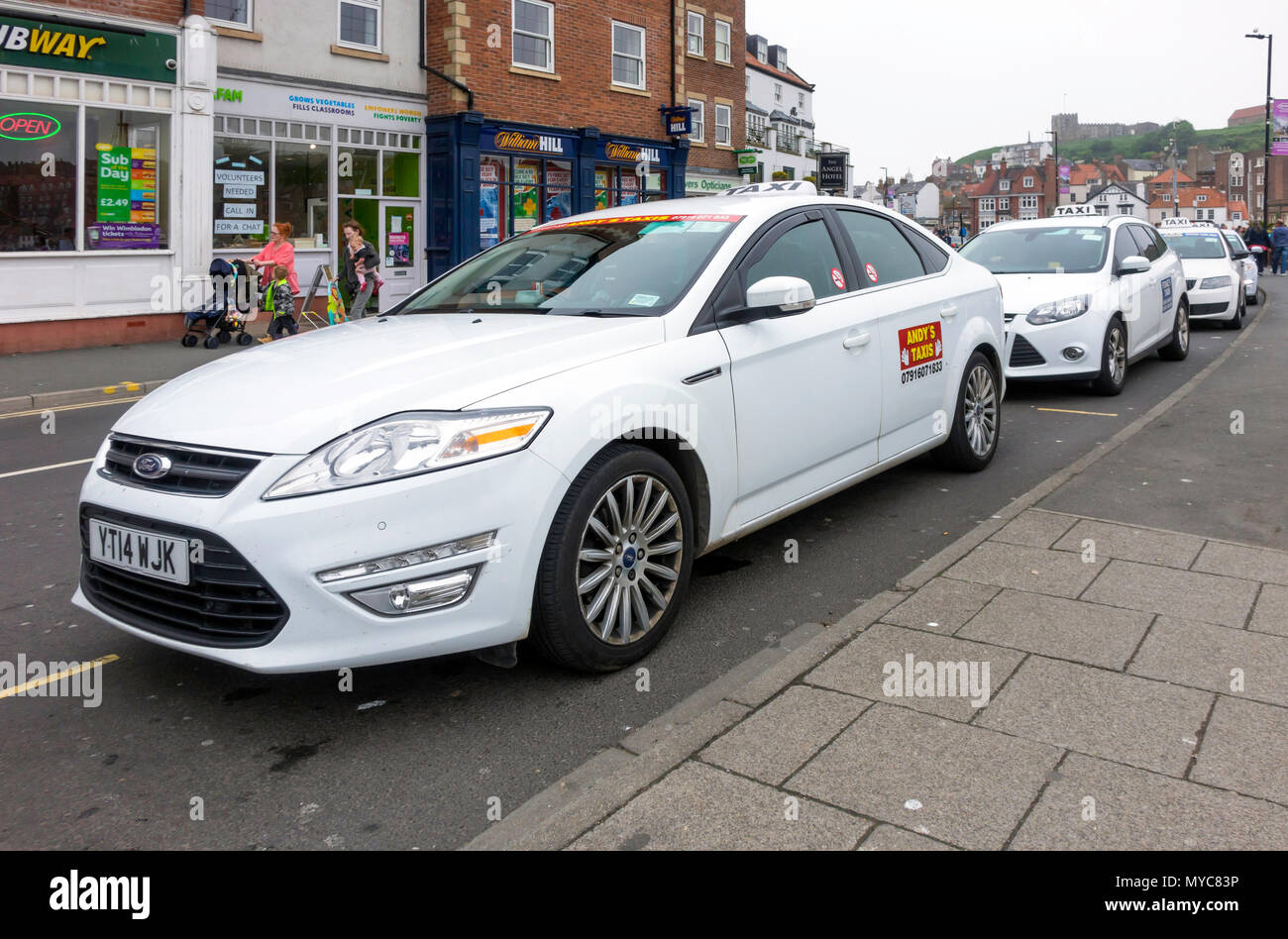 Taxi rank with white taxis waiting in New Quay Road Whitby North ...