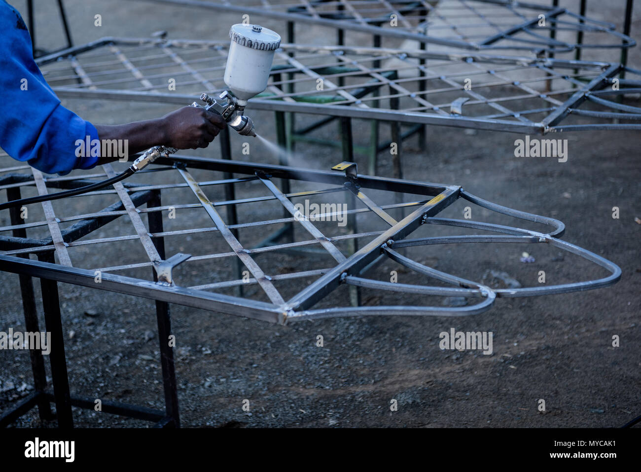 A worker sealing the metal table with a spray gun Stock Photo