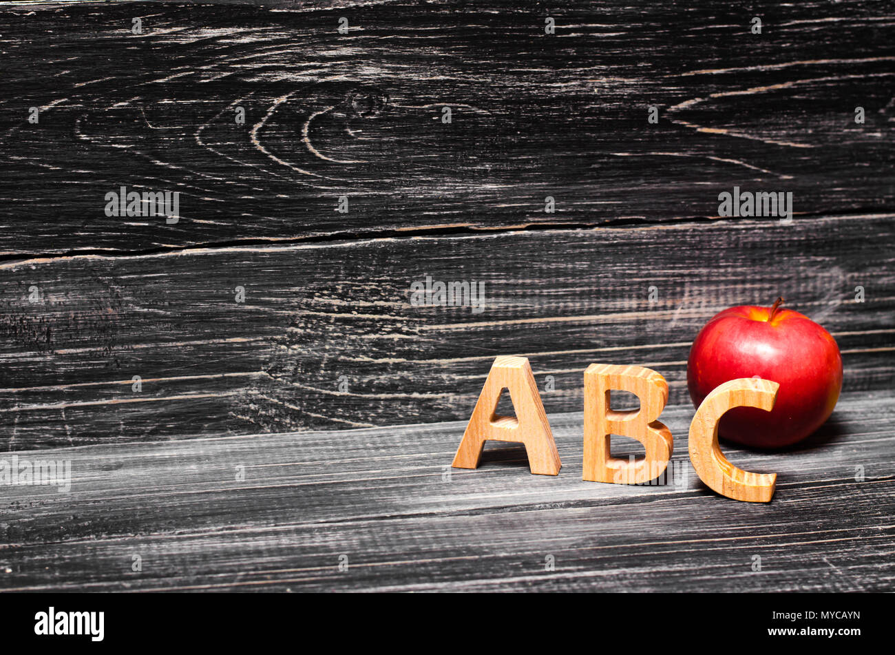 Alphabet letters and red apple on a black background. The concept of education, knowledge and science. Wooden letters, letters AB S. Retro school. App Stock Photo