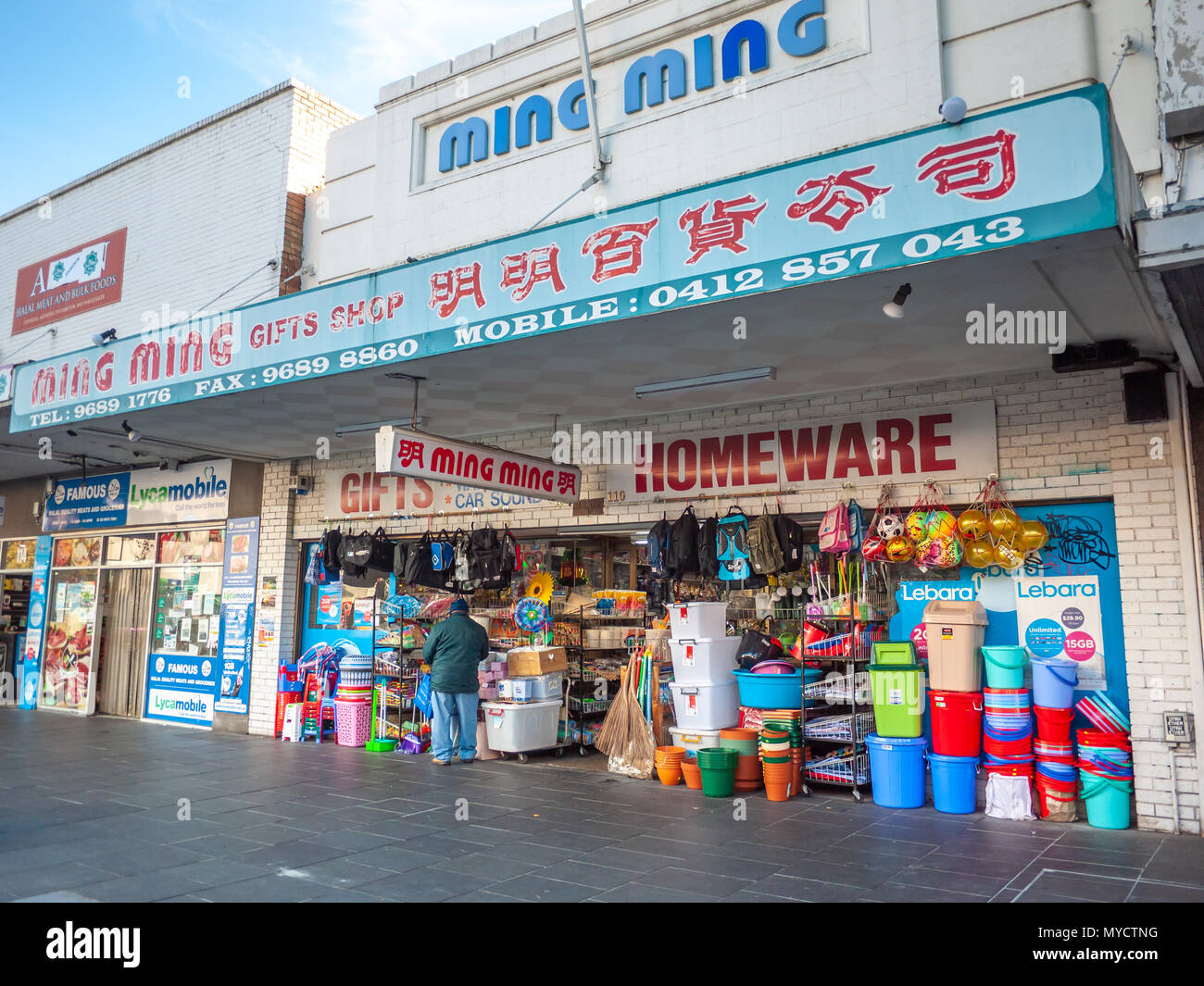 Local shop packed with a variety of cheap products in Melbourne's suburban street. Bilingual shop signs are a feature of Footscray. VIC Australia. Stock Photo