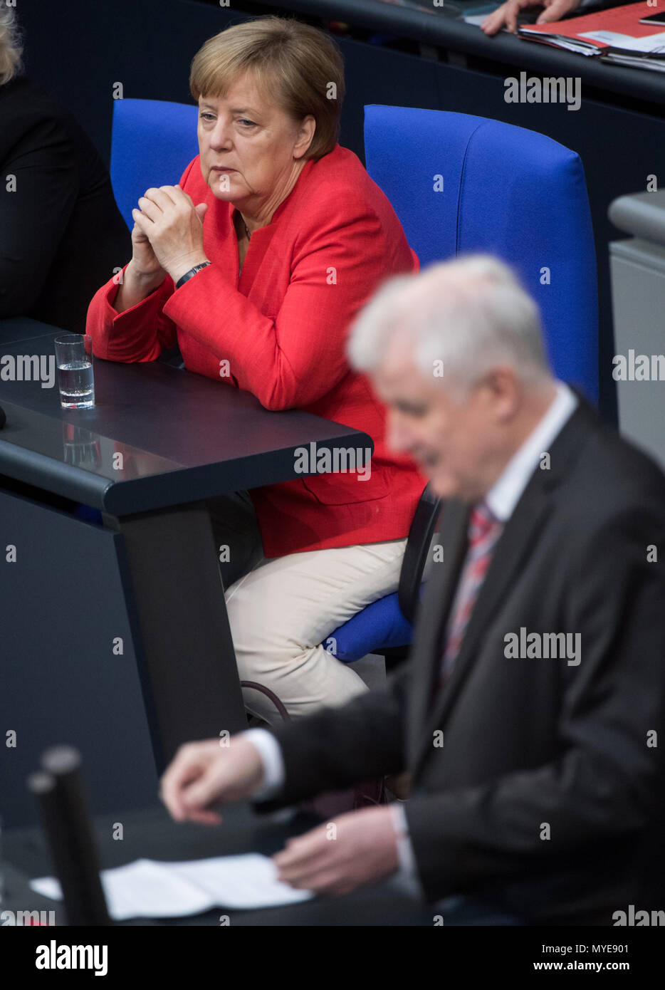 Berlin, Germany. 7th June, 2018. German chancellor Angela Merkel (Christian Democratic Union) watches as Horst Seehofer of the Christian Social Union (CSU), federal interior minister, speaks during a plenary meeting of the German parliament at the Reichstag building. Main themes of the 36th session of the 19th legislature period include new refugee family reunion laws, foreign deployments of the German army, rising rent prices in Germany as well as a committee of inquiry requested by the Free Democratic Party concerning the Federal Office for Migration and Refugees (BAMF) affair. Credit: dpa p Stock Photo