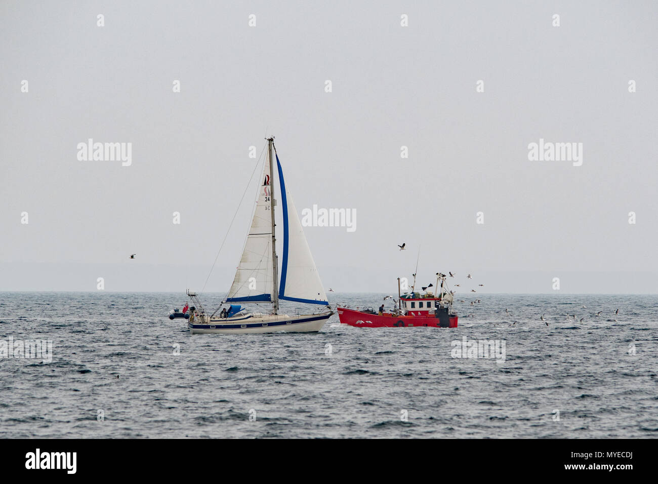 Mousehole, Cornwall, UK. 7th June 2018. UK Weather.  Despite having the entire sea at their disposal, on a grey mild afternoon, this sailing and fishing boat appeared to come perilously close to each other this afternoon. Credit: Simon Maycock/Alamy Live News Stock Photo