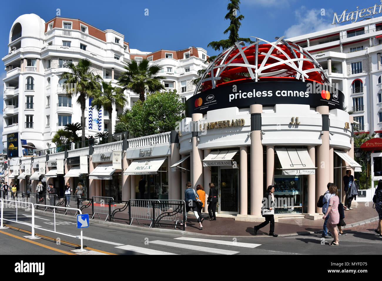 Cannes, France - May 11, 2018: Boulevard de la Croisette which contains high-end shops such as Rolex, C Gaucherand and an ad for the Film Festival. Stock Photo