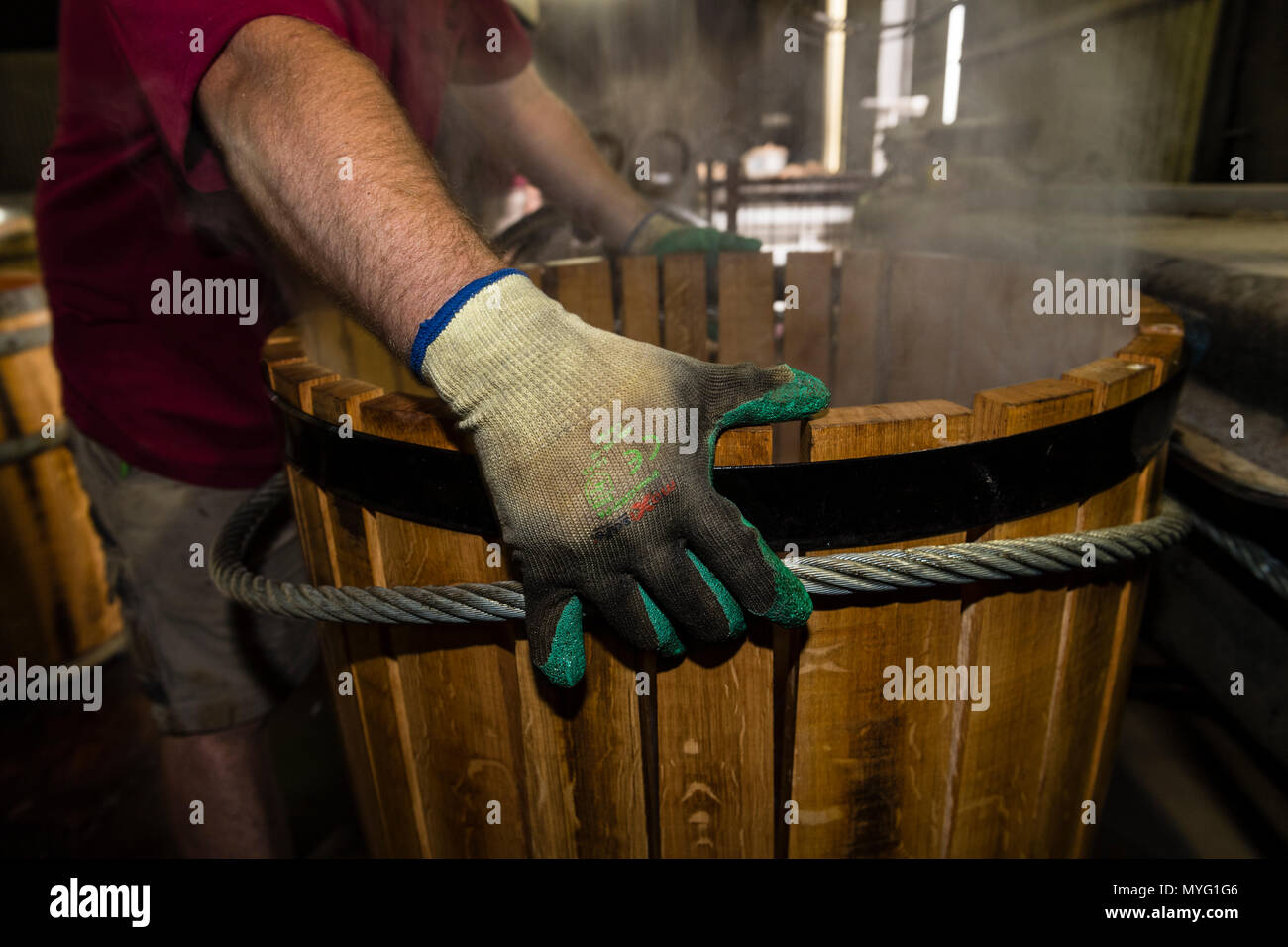 Steaming French Oak staves are pulled into shape using a cable winch to make a wine barrel. Stock Photo