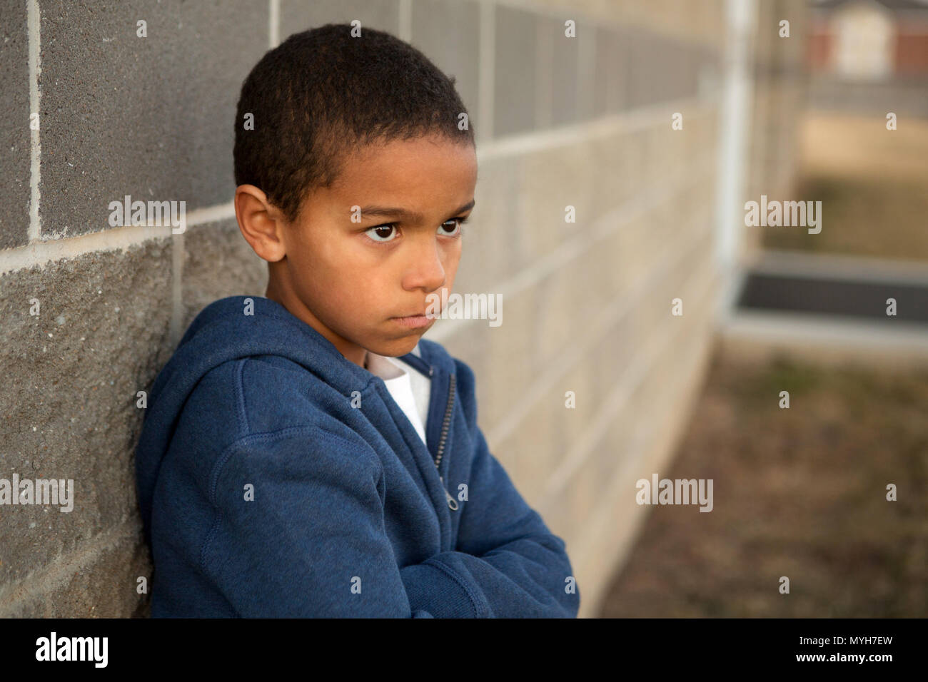 Portrait of a sad lonely little boy outside on a brick wall Stock Photo ...