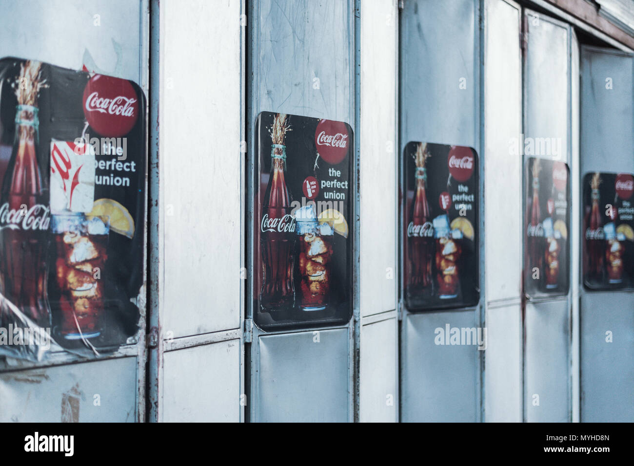Vintage Coca Cola posters advertising on steel wall. Stock Photo