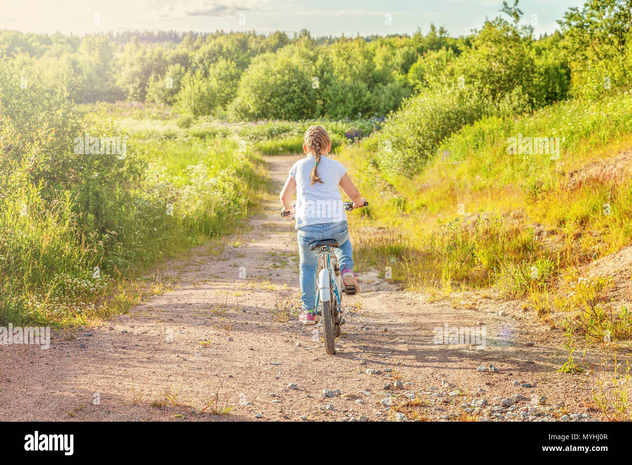 Happy child riding bike. Young girl on bicycle in sunny summer park