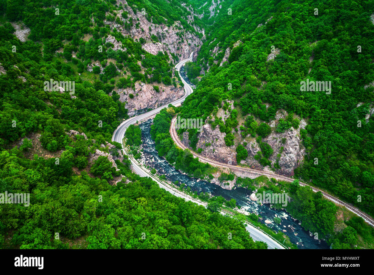 Aerial view of drone over mountain road and curves going through forest landscape Stock Photo