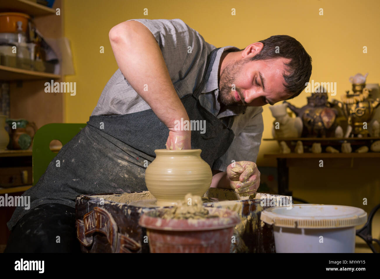Professional male potter working with clay on potter's wheel in