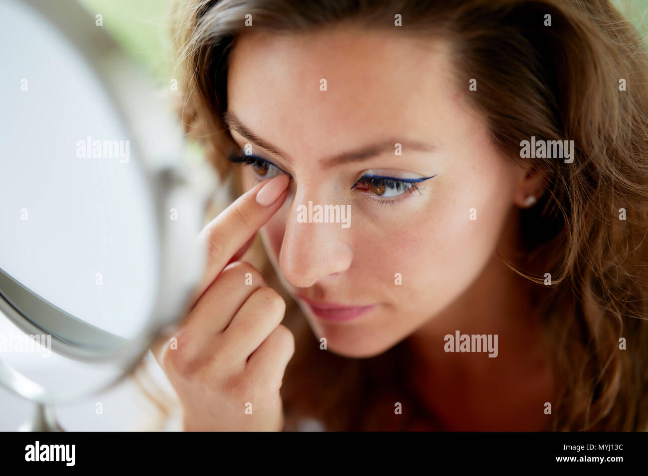 girl looking at her eyes in a mirror Stock Photo