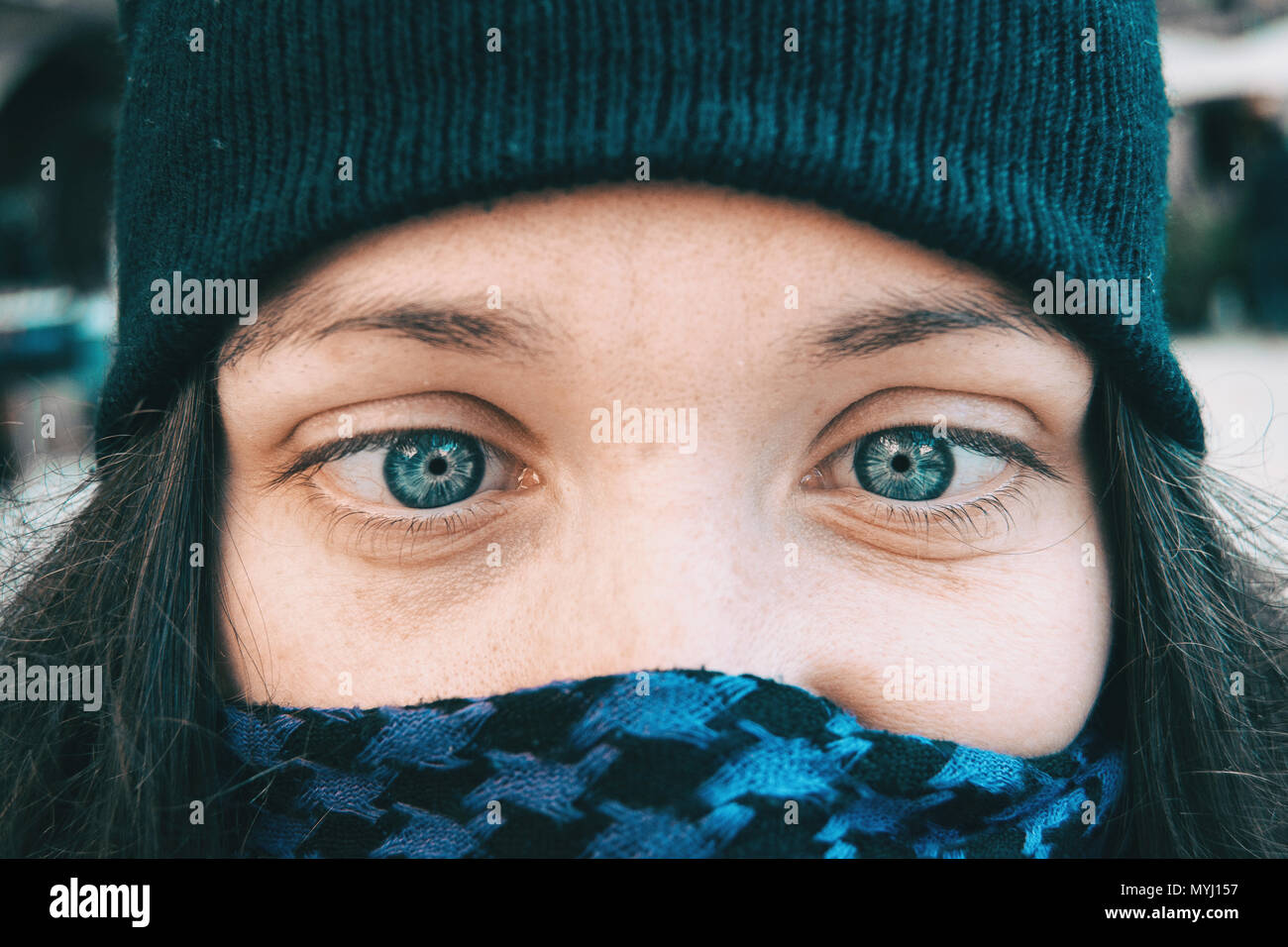 Blue-eyed girl in a winter hat playing dumb with her eyes Stock Photo