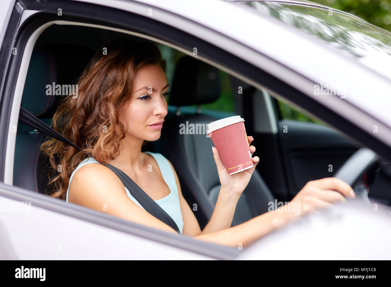 Woman drinking coffee whilst driving Stock Photo