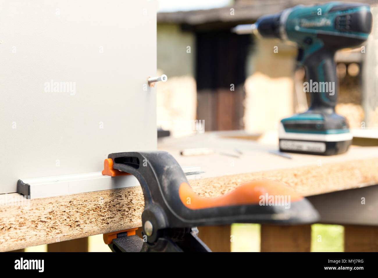 Furniture assembly. Making of kitchen using screwdriver, construction clamp and screws