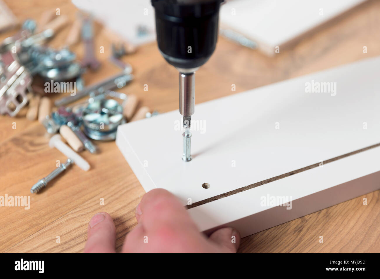 Assembling furniture from chipboard, using a cordless screwdriver Stock Photo