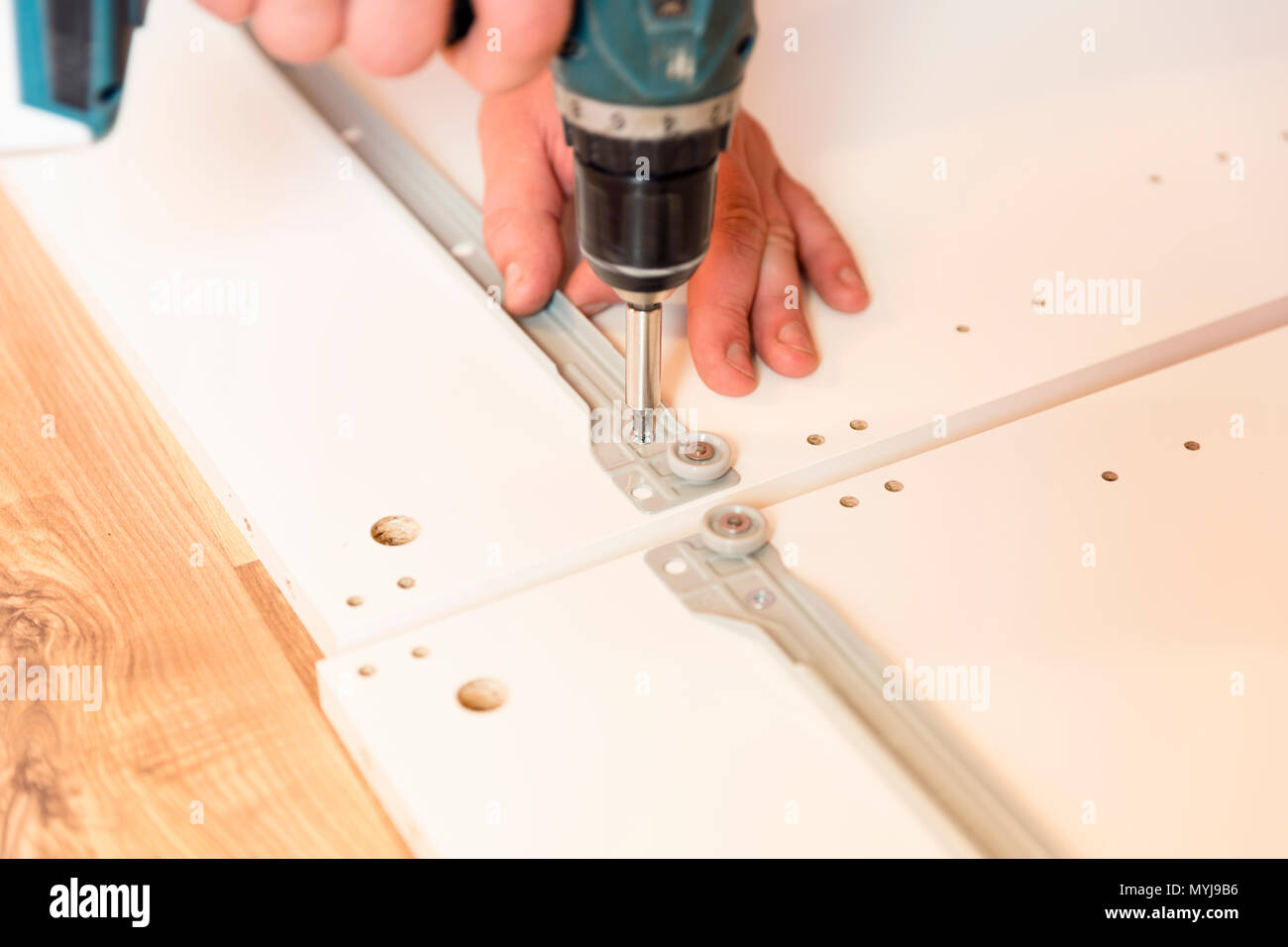 Assembling furniture from chipboard, using a cordless screwdriver Stock Photo