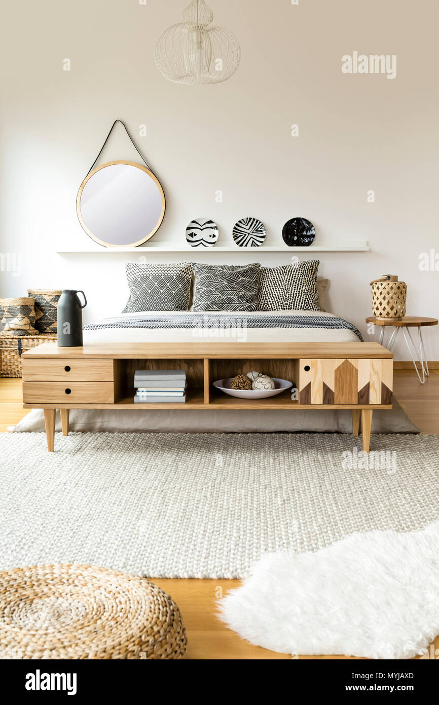 Round Mirror And Patterned Plates Above Bed In Scandi Bedroom Interior With Wooden Rustic Cupboard Stock Photo Alamy