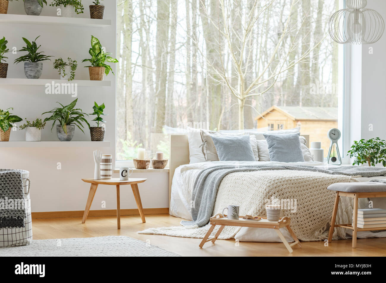 Blue Pillows On Bed Next To A Wooden Table In Natural Bedroom Interior With Plants And Window Stock Photo Alamy