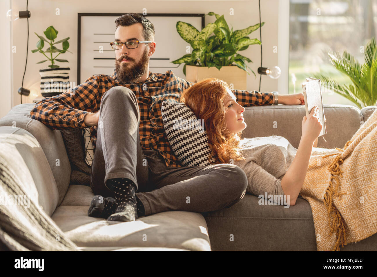 Young marriage relaxing in their free time in scandinavian style living room with modern lighting Stock Photo