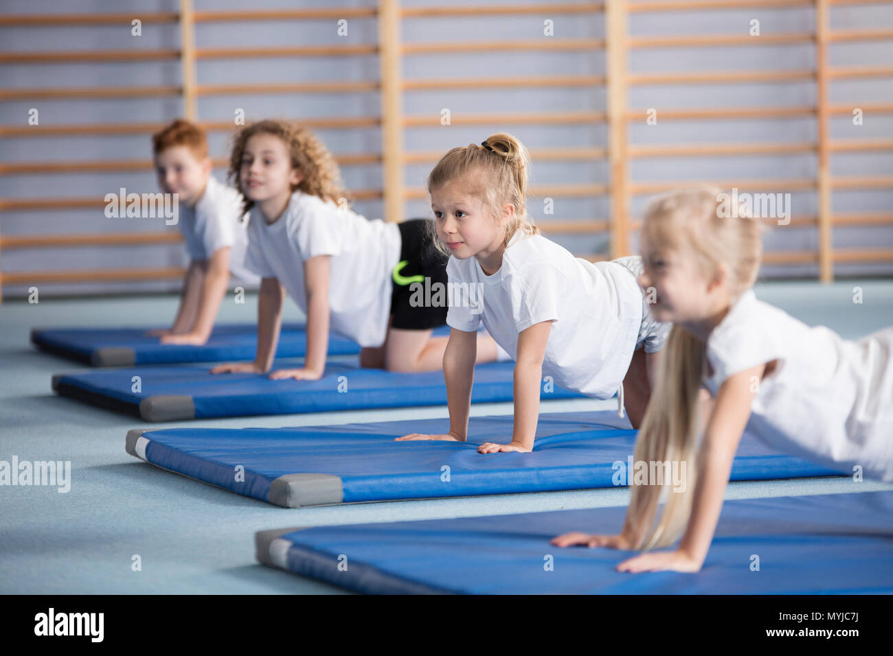 Happy girl exercising on a blue mat during corrective gymnastics classes Stock Photo