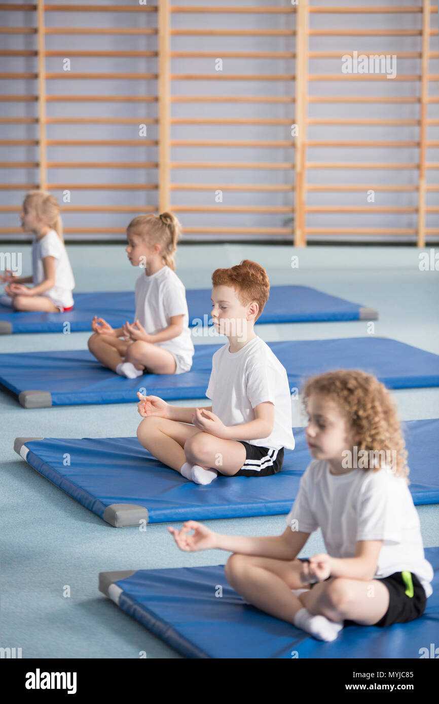 Group of kids sitting in lotus pose during yoga classes at school Stock Photo
