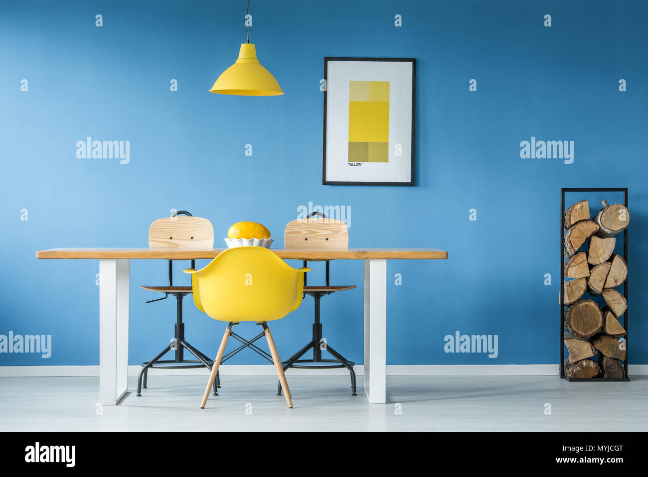 Yellow accents in a blue dining room interior with a big table, poster ...