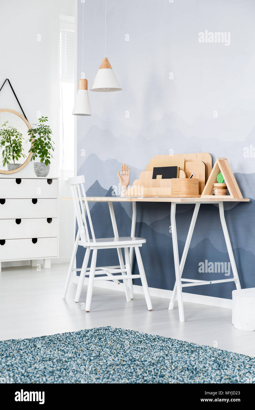 White chair at desk with wooden organizer in scandi workspace interior with mountain wallpaper Stock Photo