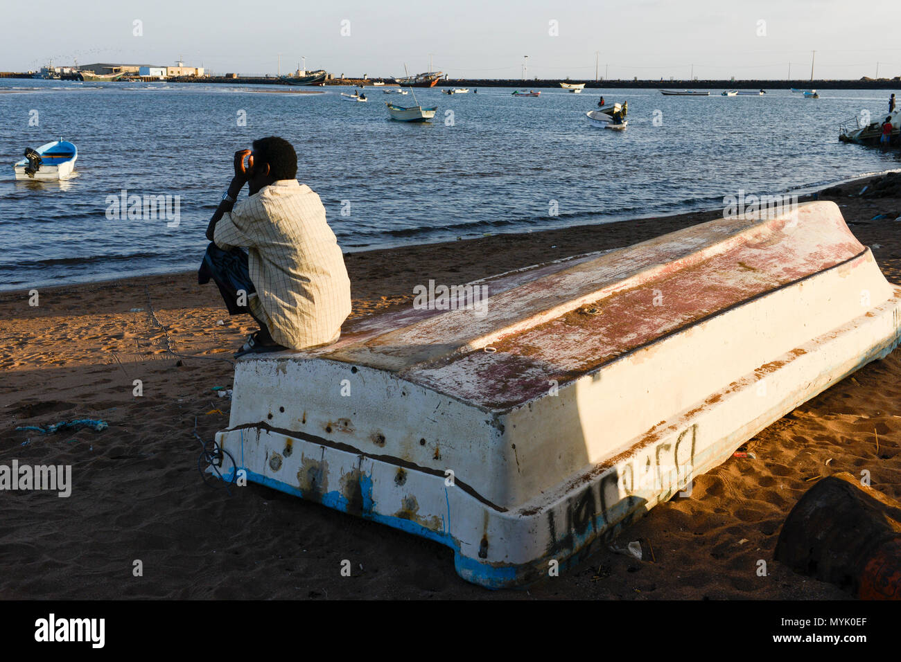 DJIBOUTI , Obock, from here ethiopian migrants try to cross bab el mandeb, red sea, gulf of aden by smuggler boats to Yemen to continue the journey to Saudi Arabia or Europe, ethiopian migrant looking to the sea / DSCHIBUTI, Obock, Meerenge Bab el Mandeb, mit Hilfe von Schleppern versuchen aethiopische Migranten hier nach Jemen ueberzusetzen, um weiter nach Saudi Arabien oder Europa zu gelangen Stock Photo