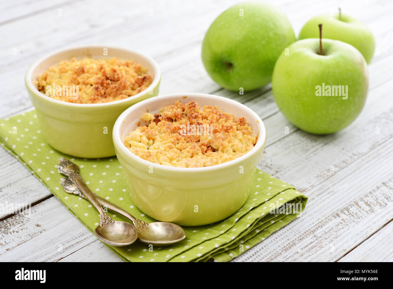 Apple crumble in small baking dish with fresh apples on wooden background Stock Photo