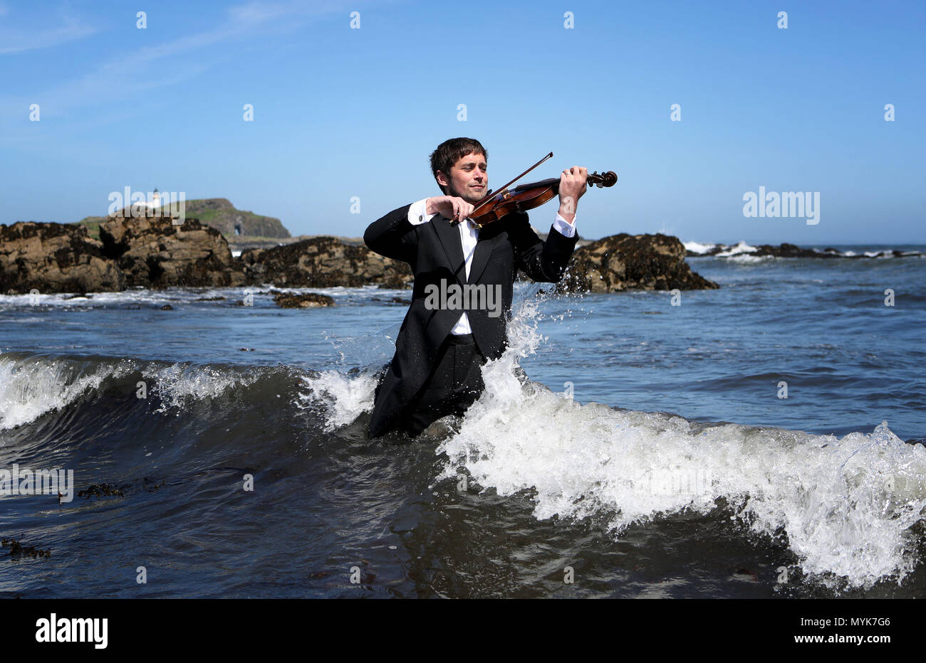Musician Thoren Ferguson plays the Il Mare Violin, which is made from driftwood in the sea at Yellowcraigs, East Lothian. Stock Photo