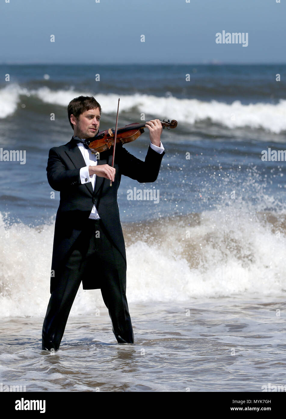 Musician Thoren Ferguson plays the Il Mare Violin, which is made from driftwood in the sea at Yellowcraigs, East Lothian. Stock Photo