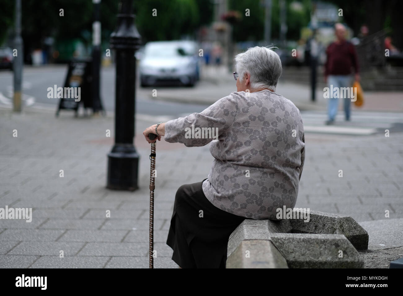 An old lady resting with her walking stick in Falmouth, Cornwall Stock Photo