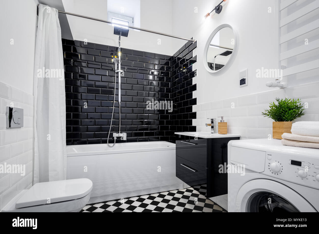 Black and white bathroom with bathtub, toilet and washer Stock Photo