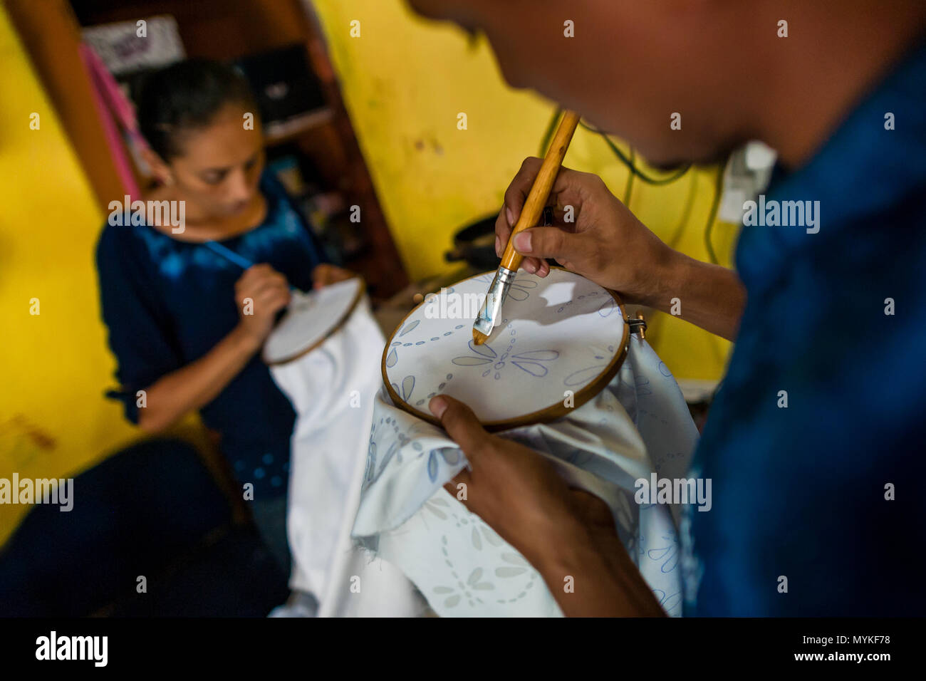 A Salvadoran man draws the wax onto a fabric, dyed with a natural blue indigo afterwards, in a clothing workshop in Santiago Nonualco, El Salvador. Stock Photo
