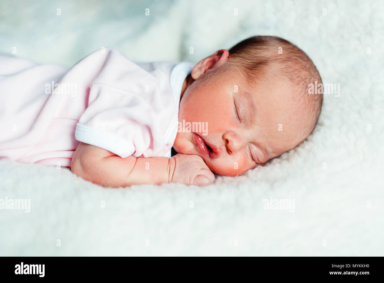 Soft portrait of peaceful sweet newborn infant baby lying on bed while