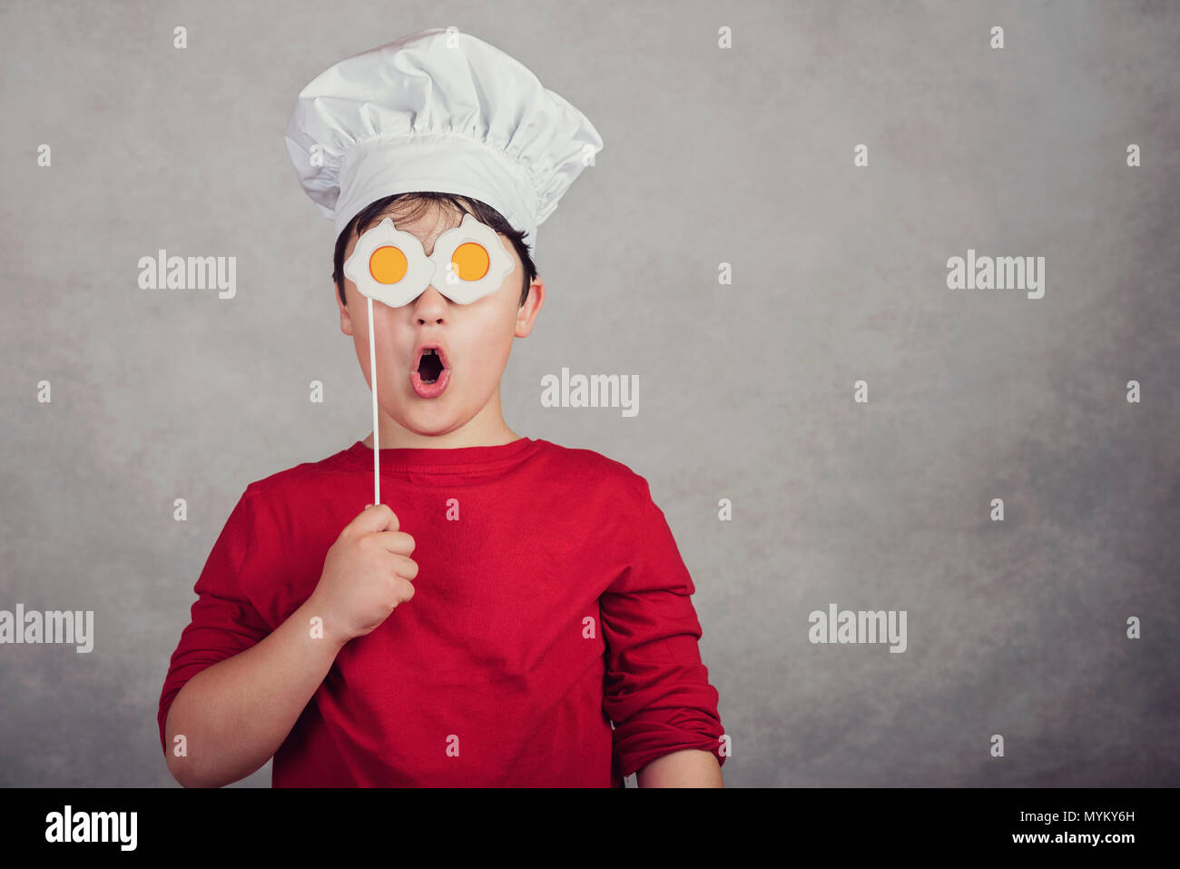 funny child with fried eggs in his eyes on gray background Stock Photo