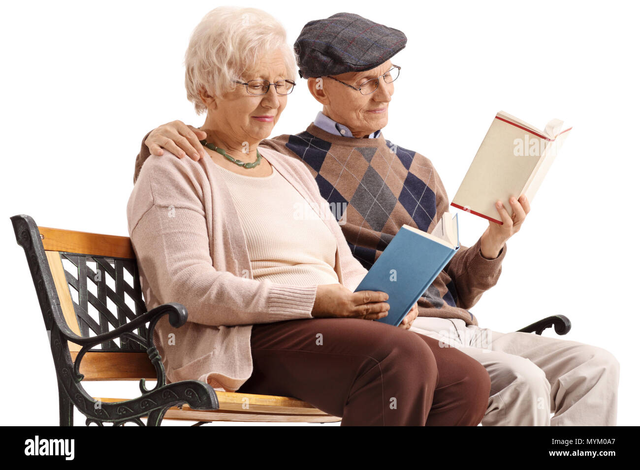 Elderly couple seated on a bench reading books isolated on white background Stock Photo