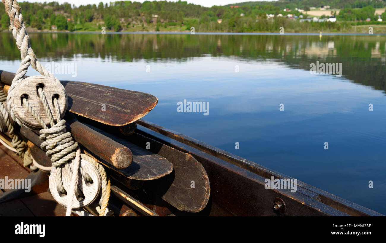 Well used wooden oars and ropes on a Viking ship replica. Coastland in the background. Stock Photo